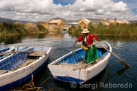 Una mujer vestida con trajes típicos regionales navega con su barca entre las islas de los Uros.